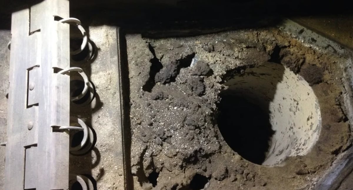 Pelletsheizung vor der Reinigung – verschlissene Betonoberfläche mit Löchern neben Metalllineal