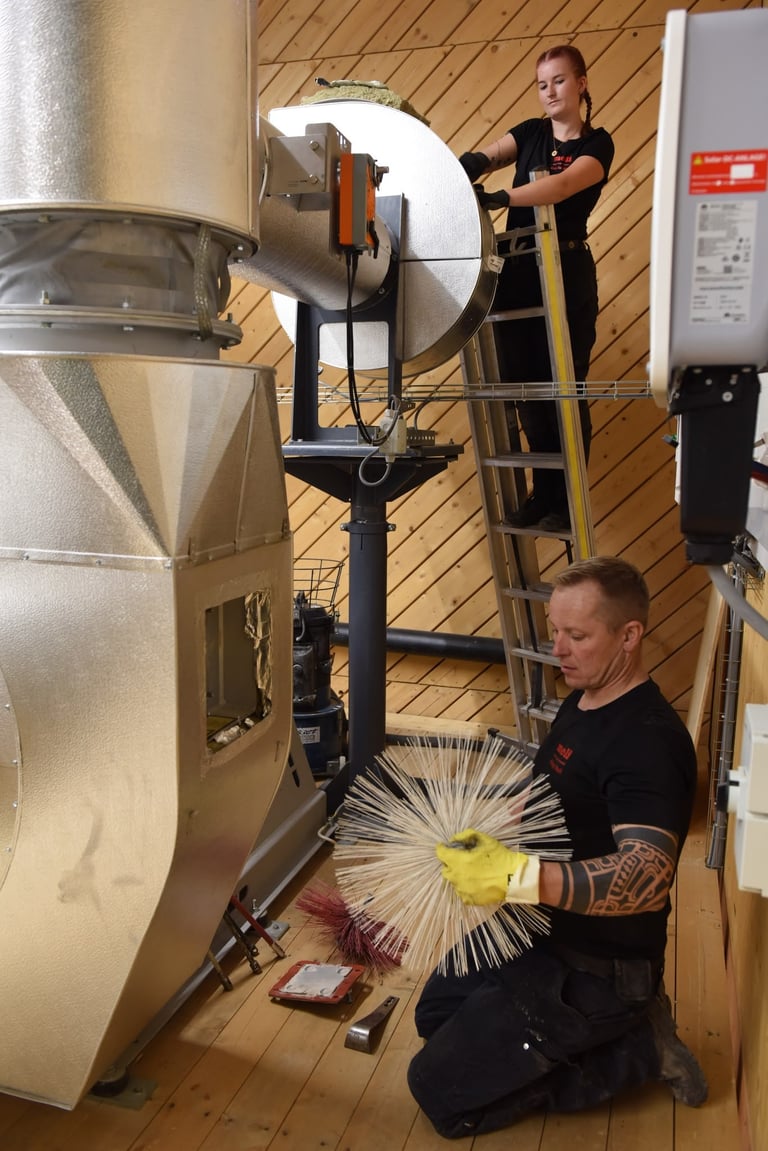 Zwei Arbeiter warten eine grosse industrielle Kaffeeröstmaschine in einer Holzwerkstatt